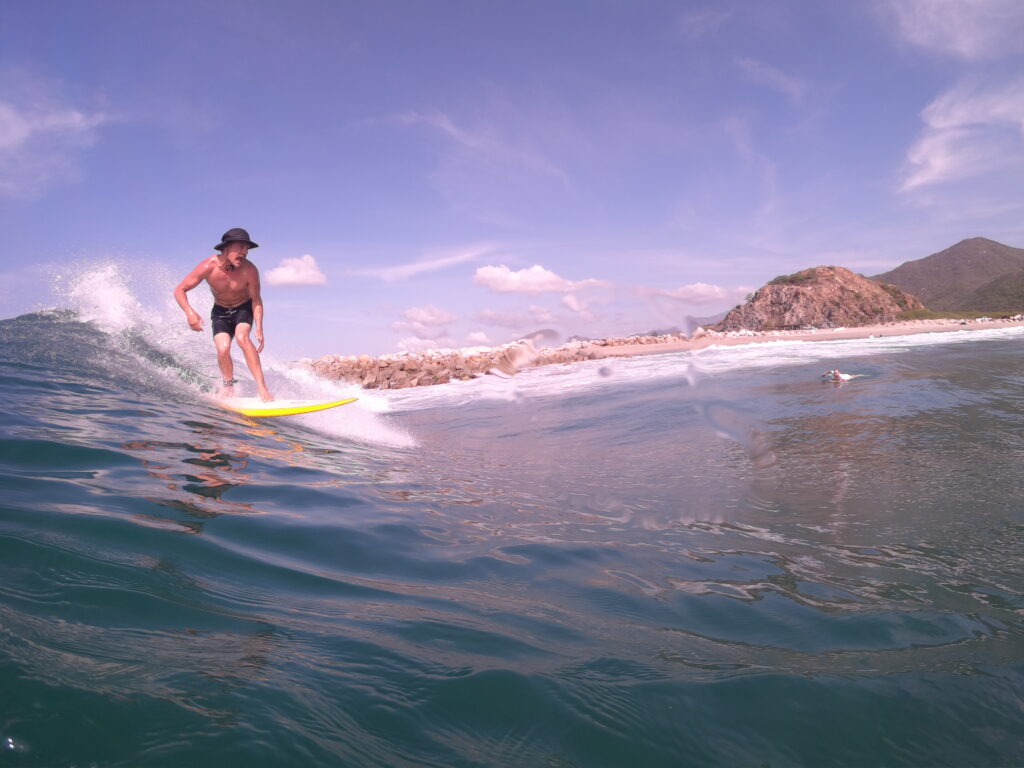 Surfer riding a perfect wave in Salina Cruz with clear blue water and rugged cliffs in the background