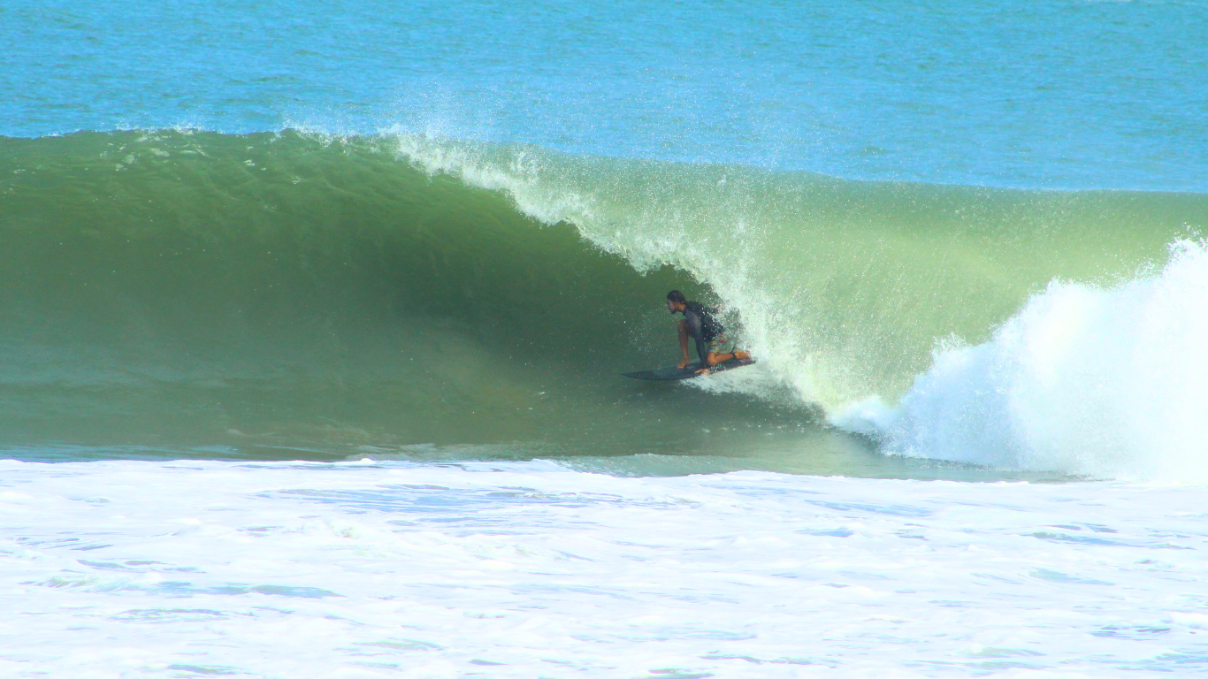 "A skilled surfer riding deep inside a powerful barrel wave in Salina Cruz, Oaxaca. The crystal-clear wave forms a perfect, hollow tube as the surfer gracefully maneuvers within the barrel, with the sun shining through the translucent water."