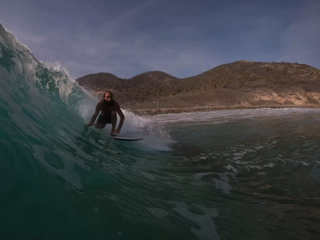 Surfer paddling out to an uncrowded wave at a secret surf break in Salina Cruz